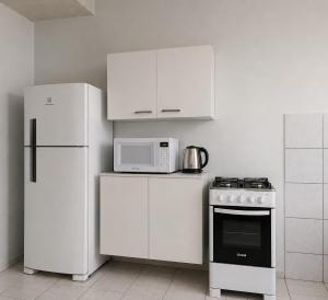 a kitchen with white cabinets and a stove and refrigerator at ParaHouse in Joinville