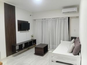 a living room with a white couch and a flat screen tv at Ayres Apart in Chivilcoy