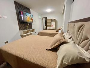 a bedroom with two beds and a flat screen tv at Olive Loft - Local Sensory and Boutique Experience in Tacna