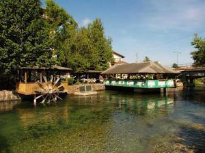 a boat parked next to a restaurant on a river at Hotel Rimski Most in Sarajevo