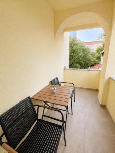a wooden table and two chairs on a balcony at Apartmani Morѐll in Novalja