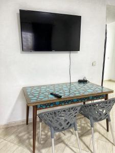 a table with a glass top and a tv on a wall at la corniche de tanger in Tangier