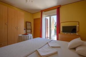 a bedroom with a bed and a tv and a window at Room Marta in Omišalj