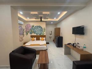 a bedroom with a bed and a couch and a tv at Jay & Jas Hotel in Tirupati