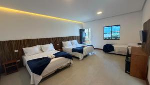 a hotel room with two beds and a flat screen tv at Pousada Ville Solare Garden in Santo Amaro