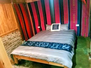a small bed in a room with a striped wall at May Lai Homestay in Tả Van