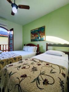 a bedroom with two beds and a ceiling fan at Pousada Alecrim Dourado in Paraty