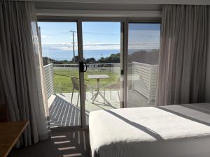 a bedroom with a bed and a balcony with a view at Beachfront Bicheno in Bicheno +41 photos