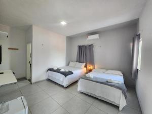 a hotel room with two beds and a table at Pousada Ville Solare Garden in Santo Amaro
