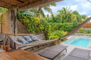 a hammock on a porch next to a swimming pool at Breeze Ocean Bungalow Moorea in Moorea
