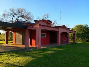 a small red building with a grass yard at La Chacra de Pilar in Pilar +12 photos