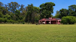 a red house with two horses in a field at La Chacra de Pilar in Pilar