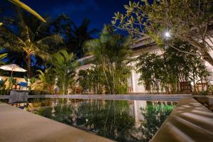 a swimming pool in front of a building with palm trees at Drift Hideaway- Adult only in Kuta Lombok