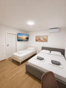 a bedroom with two beds and a chair in it at Apartmani Morѐll in Novalja
