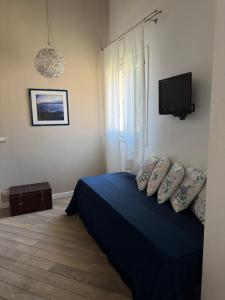 a bedroom with a blue bed and a tv at Le Lumie in Modica