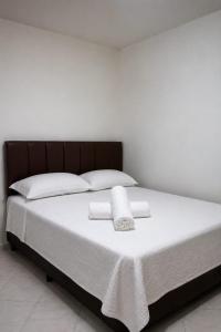 a bed with white sheets and two towels on it at Pousada Quixadá Central in Quixadá
