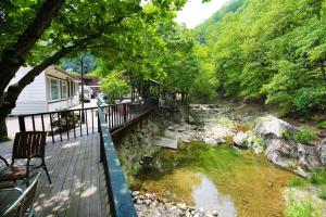 a deck with a bench next to a river at gapyeong semmul pension in Gapyeong