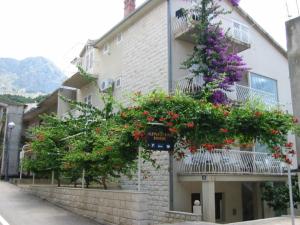 un edificio con plantas en flor a su lado en Apartment Lidija en Podgora