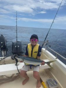 a young boy holding a fish in a boat at Ucuilagi Resort in Matei