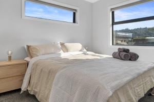 a bedroom with a bed with two towels on it at Recline on Leo in Waihi Beach
