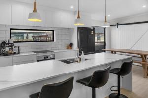 a kitchen with a white counter and some chairs at Recline on Leo in Waihi Beach +13 photos