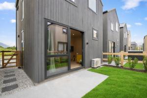 a gray house with a yard with green grass at Ski Villa with Carpark 40, Stylish Alpine Base in Queenstown