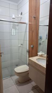 a bathroom with a toilet and a shower and a sink at Suíte privativa com acesso à rua in Dourados