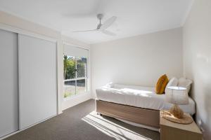 a white bedroom with a bed and a window at Skippers Place in Noosaville +15 photos
