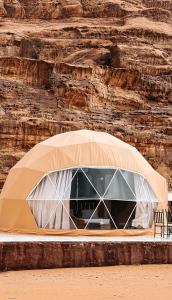 a tent in front of a rock wall at Natalie Wadi Rum camp & Jeep tour in Wadi Rum