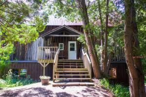 a log cabin with stairs leading up to the front door at The Barn - A Unique Gathering Place in Sainte-Cécile-de-Masham