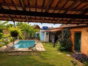 a backyard with a swimming pool and a house at Guest House Flor de Laranjeira in São Pedro da Aldeia