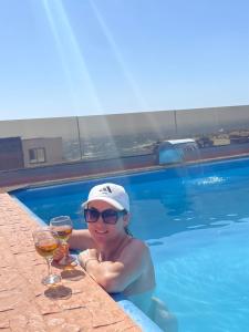 a woman holding two glasses of wine in a swimming pool at Dar-Vida Guesthouse in Imsouane