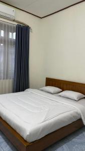 a bedroom with a bed with white sheets and a window at Cendana Guesthouse Labuan Bajo2 in Labuan Bajo
