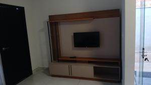 a living room with a television on a wall at New House, Long Stay in Maringá