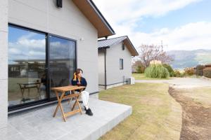 a woman sitting at a table in front of a house at Green Peak 2 in Aso