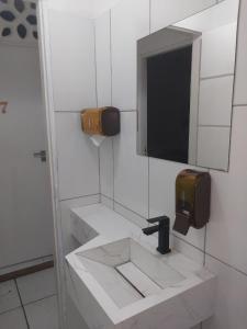a bathroom with a sink with a television on the wall at Fênix hospedaria in Natal +66 photos