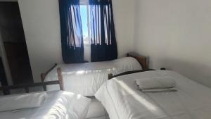 a room with two beds and a window with blue curtains at Dpto GAMA a cuadras del corso in Gualeguay