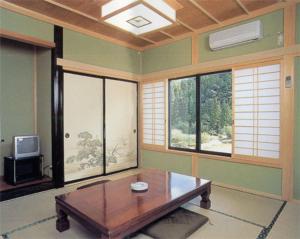 a living room with a wooden table and windows at Minshuku Ryokan Kawai in Shinshiro