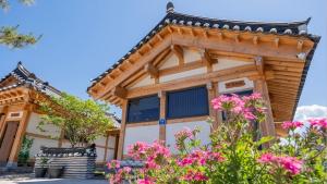 a wooden house with pink flowers in front of it at Hanok Stay ieum in Gangneung