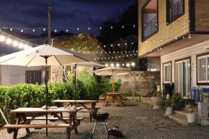 a patio with picnic tables and umbrellas at night at Stay Suncheon in Suncheon