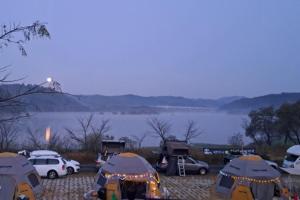 a group of cars parked in a parking lot next to a lake at Seocheon Water Willow Pension in Seocheon +4 photos