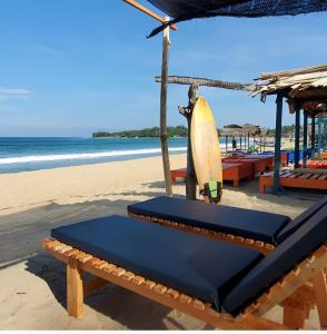 a bench with a surfboard on the beach at Surf and stay A- Bay in Arugam Bay
