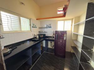 a kitchen with black counter tops and a refrigerator at Cave View Homestay in Badami