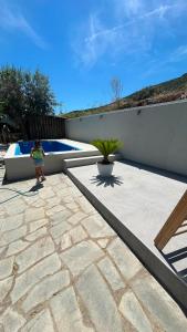 a little girl standing on a patio next to a pool at SeaViewPeramou in Elevtheraí
