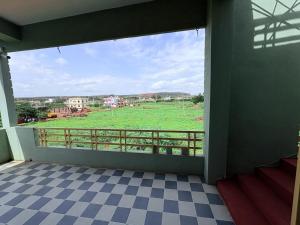 a room with a view of a field from a balcony at Cave View Homestay in Badami