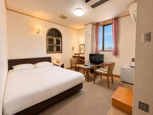 a bedroom with a bed and a desk with a television at 和洲館ホテル in Gyōda