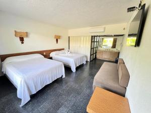 a hotel room with two beds and a couch at Hotel Bali-Hai Acapulco in Acapulco