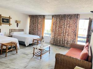 a hotel room with two beds and a couch at Hotel Bali-Hai Acapulco in Acapulco