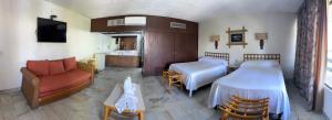 a hotel room with two beds and a couch at Hotel Bali-Hai Acapulco in Acapulco
