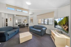a living room with two blue couches and a tv at Sovereign Views Apartments in Ballarat
